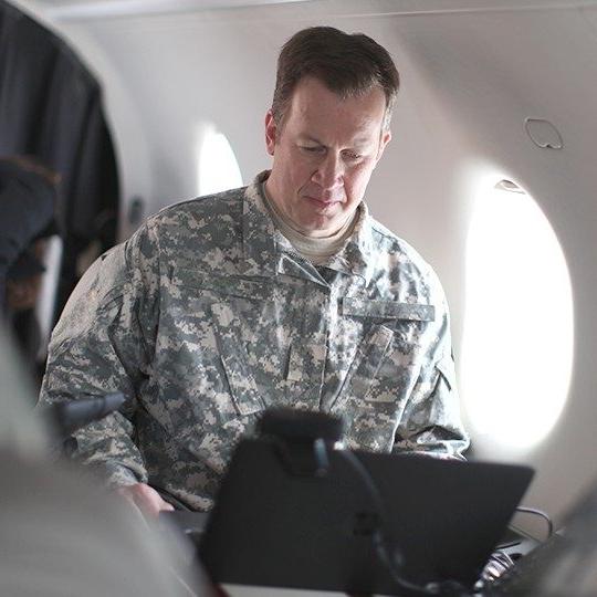 Warfighter connected to his laptop while flying on a government aircraft equipped with dual-band antennas