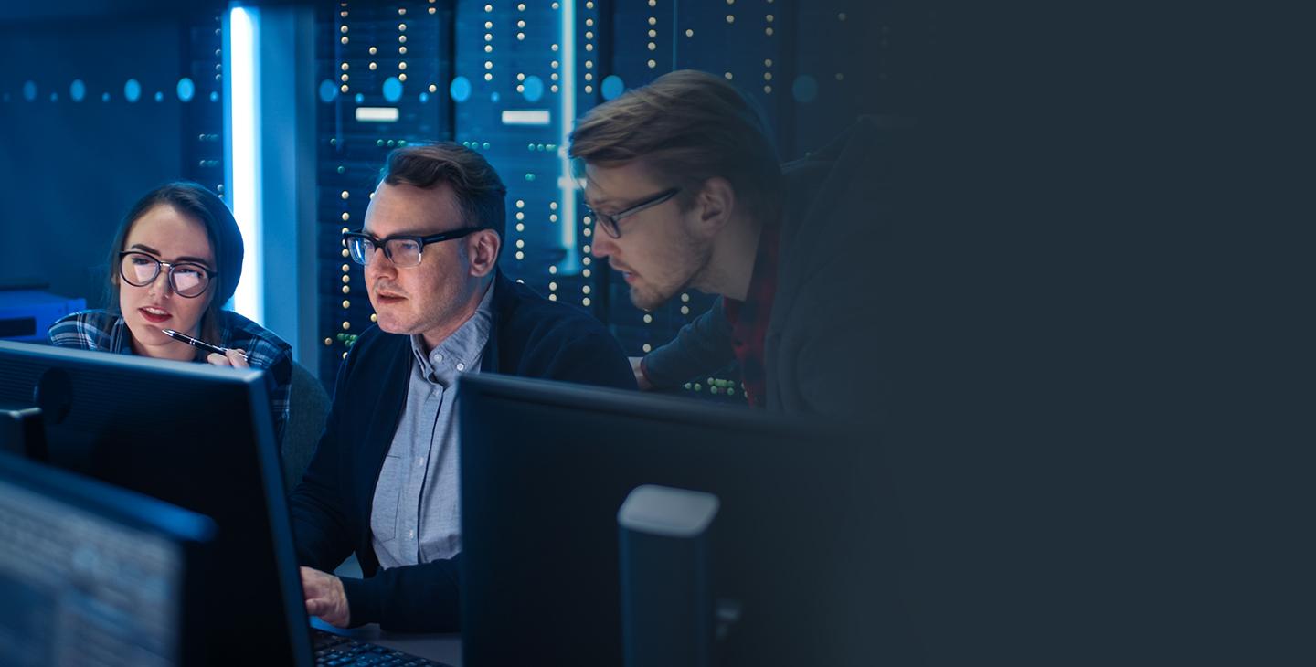 Two male and one female employees sitting behind computer monitors in a managed security room 